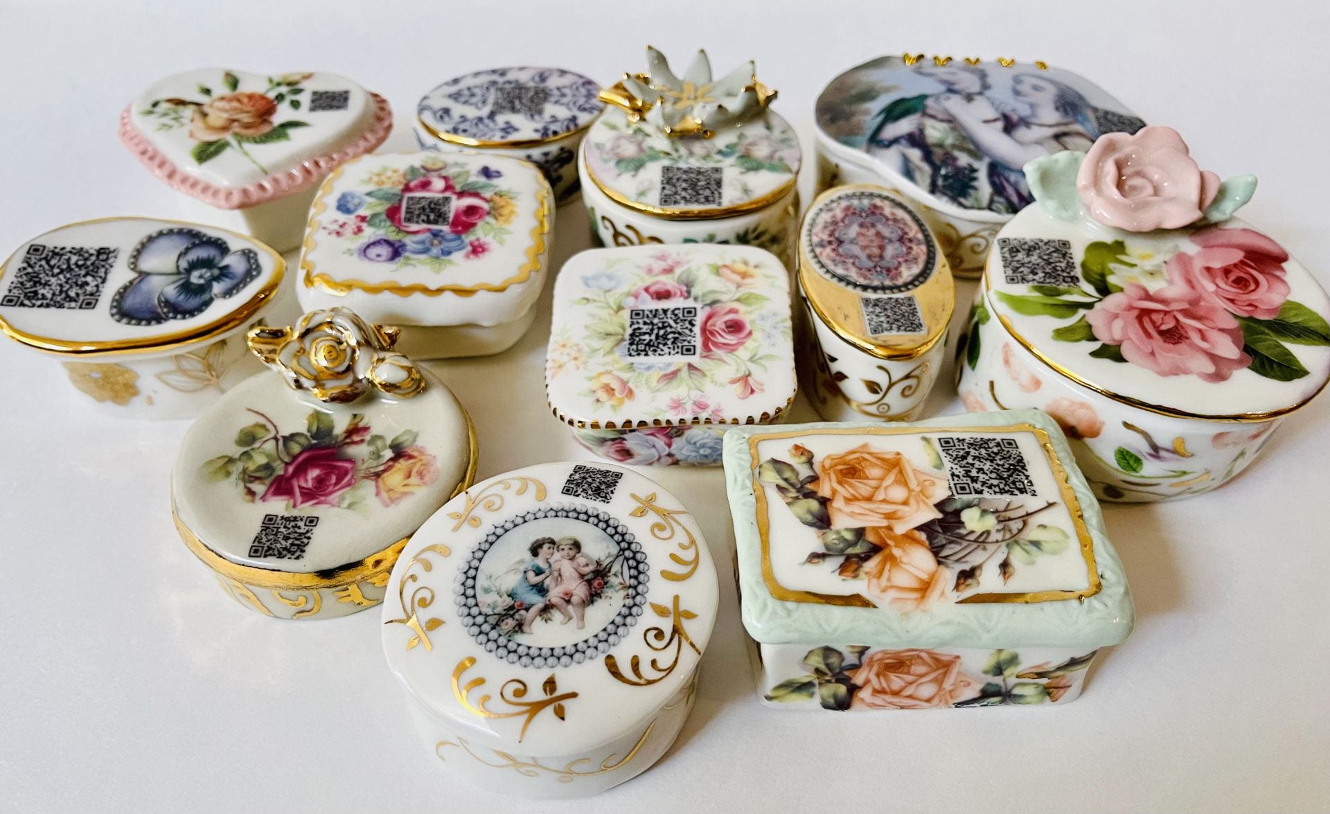 Twelve porcelain floral pillboxes with a QR code on their lids