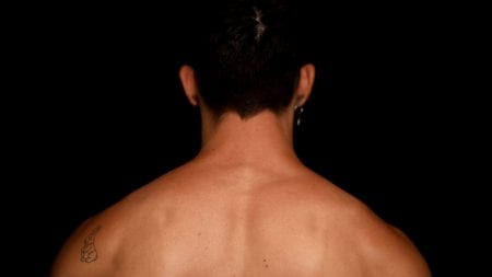 Back of a person's head with shoulder and neck showing. They have defined musculature and a tattoo of a rabbit.