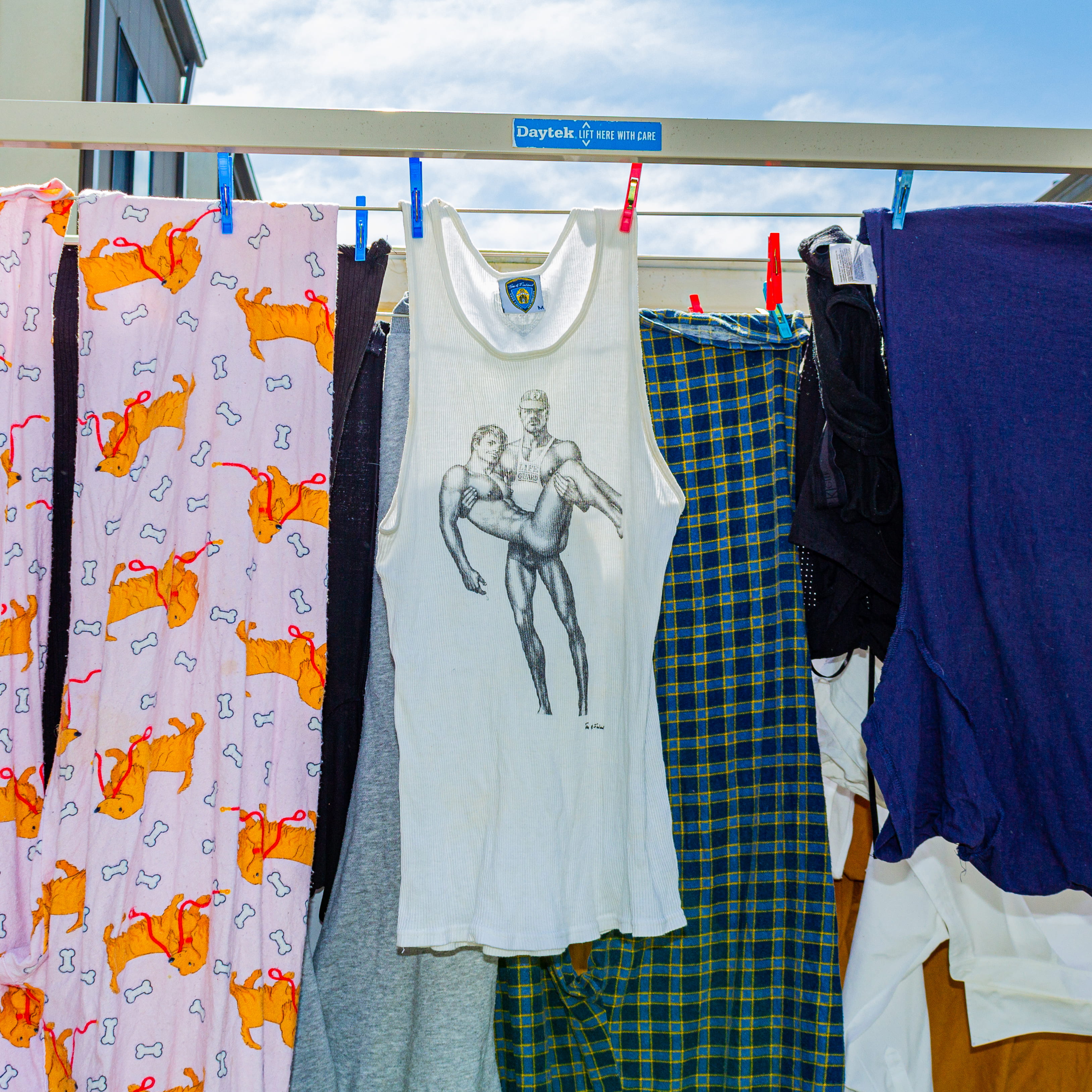 Photograph of a washing line with various clothes featuring a Tom of Finland design tank top