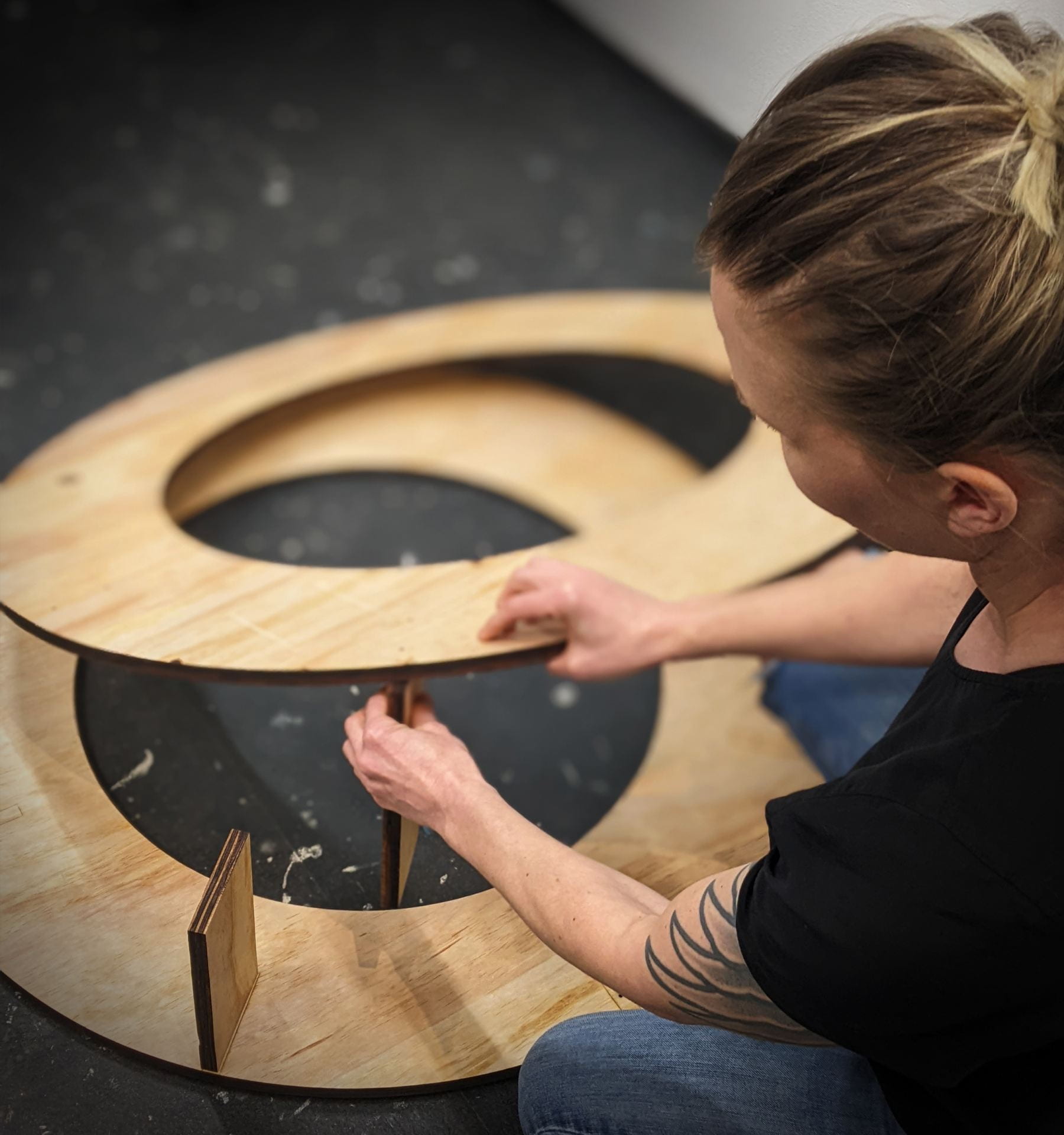Photo gallery of the artist assembling a wooden structure and holding acrylic disks