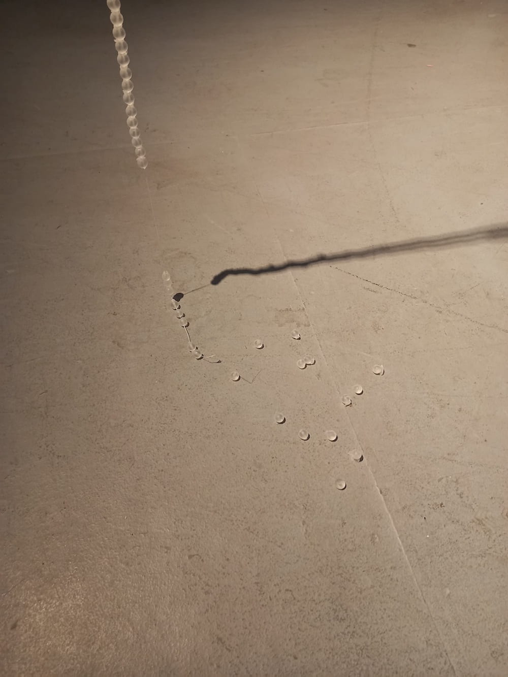 Grey floor with glass-like beads near a thread & shadow
