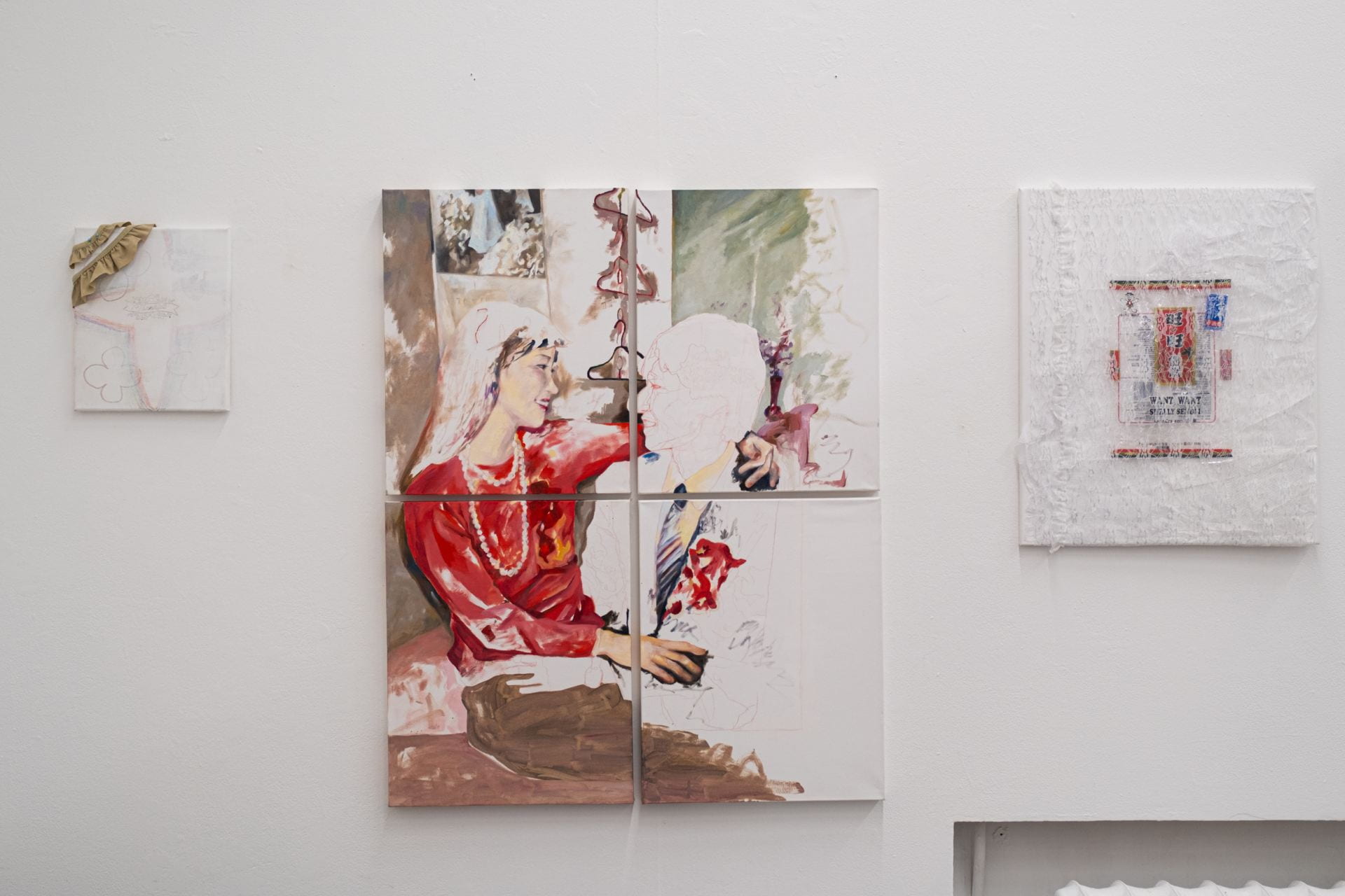 Installation view of three canvases horizontally installed on the wall. From left to right, there is a small painting with a "Thankful" sticker in the middle of the work. In the centre, there is a portrait oil painting of two figures, one of the figures has been left intentionally blank. On the right, there is a lace wrapped medium sized canvas with a chinese snack encased in the centre.