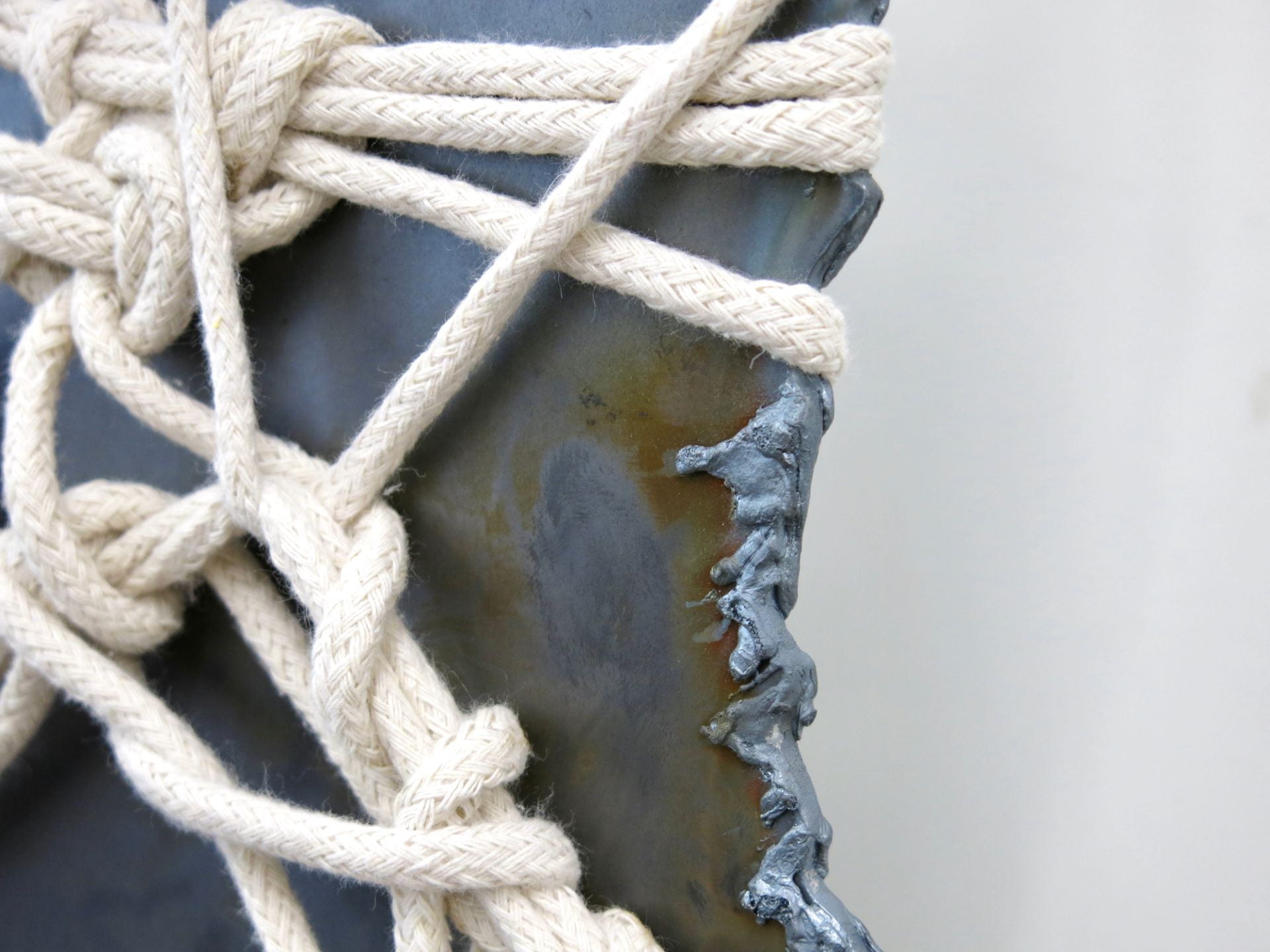 Photograph of melted metal sheet bound with rope