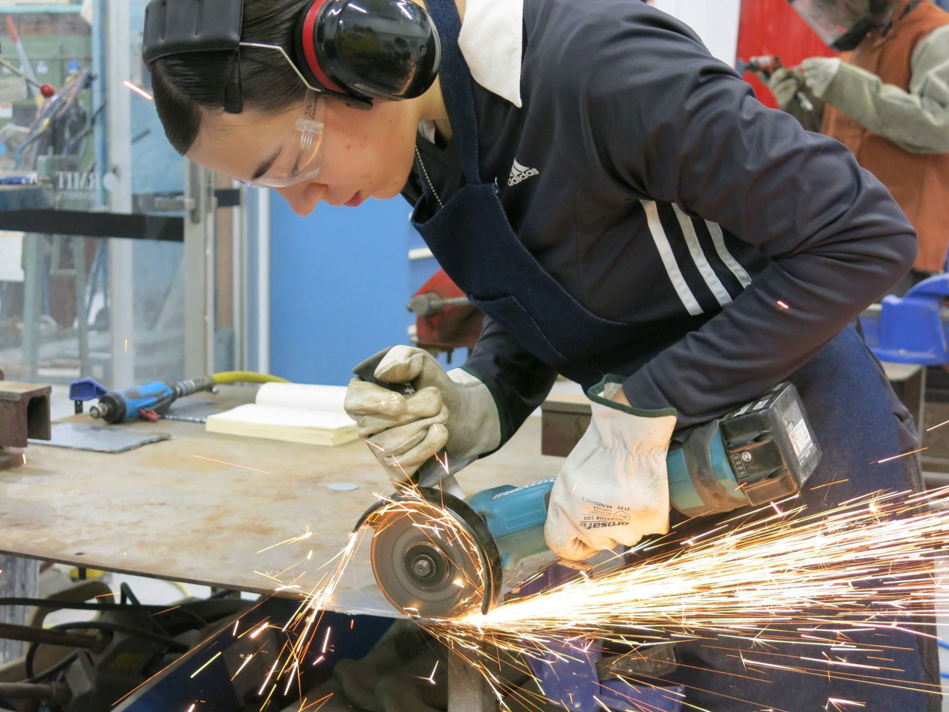 Photograph of Yvonne using the angle grinder in the metal workshop