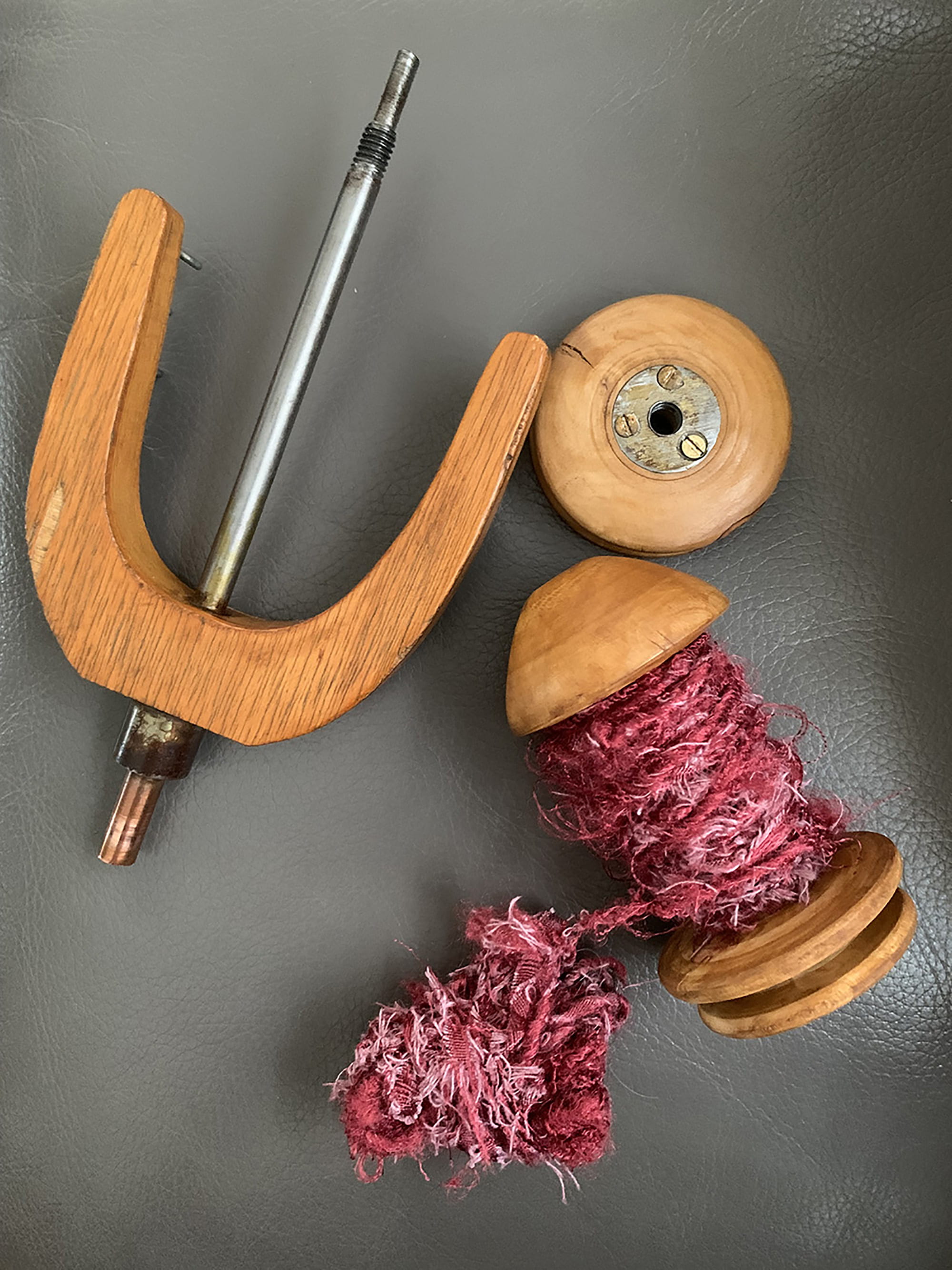 Spinning wheel spindle and bobbin containing spun rag yarn.