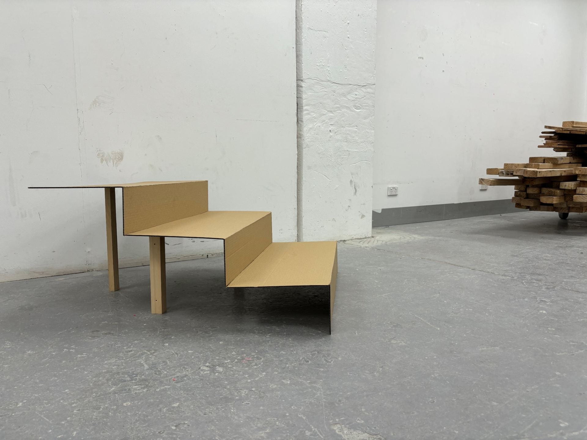 A cardboard model of a stair resting on wooden posts