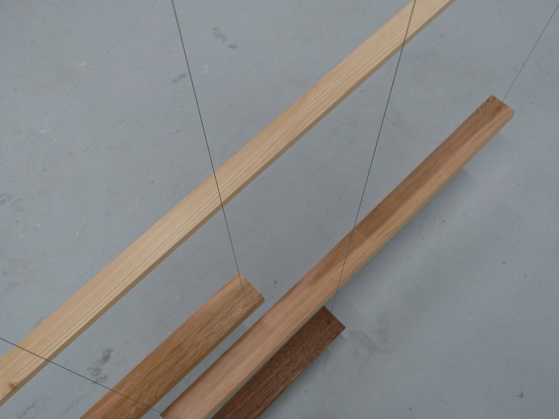 Four pieces of wood suspended by steel wire.