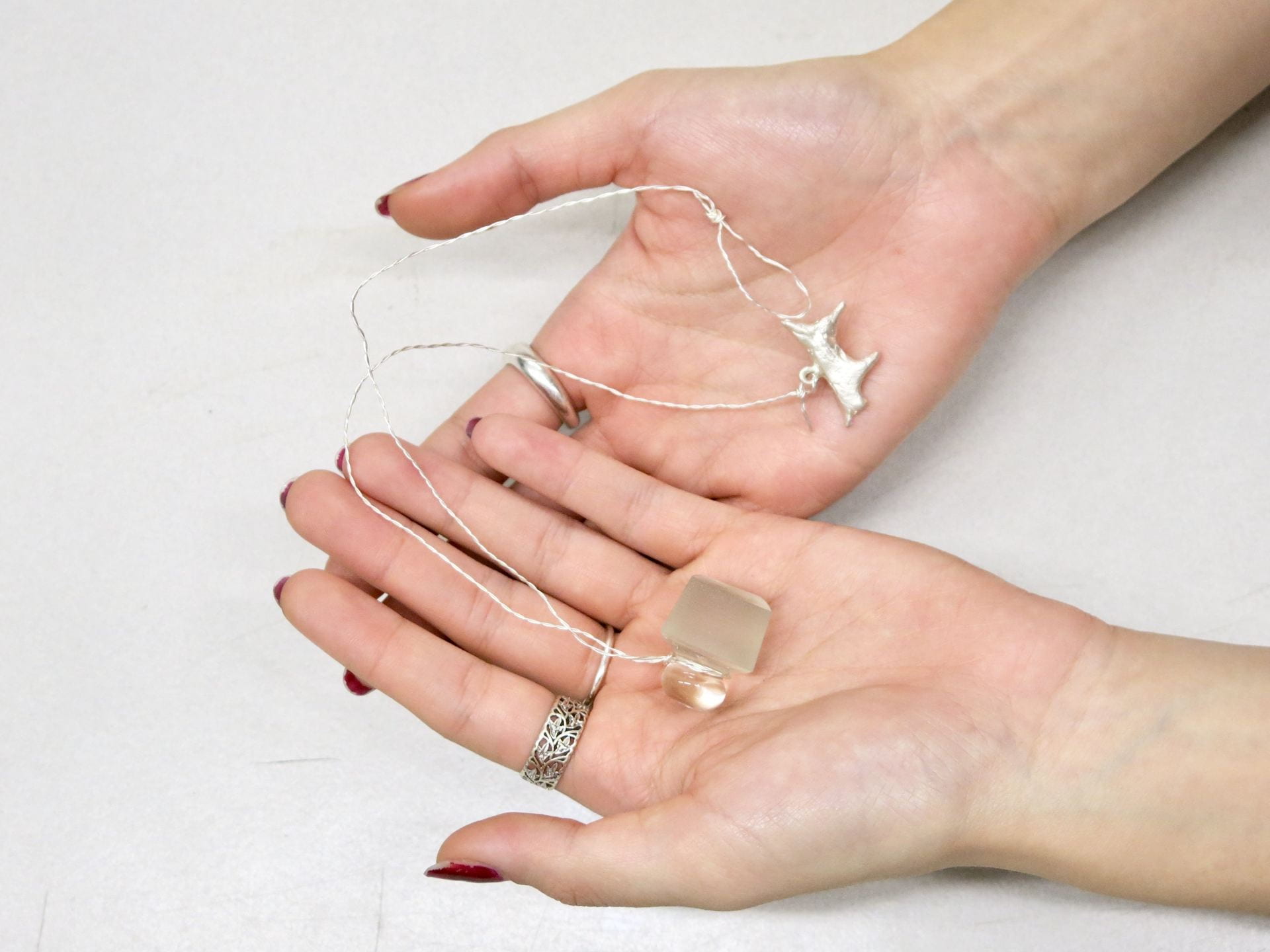 Hands holding a silver wire necklace